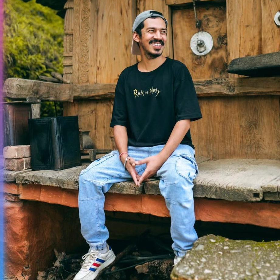 Man sitting on a wooden bench in front of a rustic wooden building